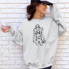 a woman wearing a sweatshirt with the number 42 on it and holding a wine glass