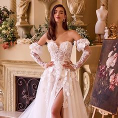 a woman standing in front of a painting wearing a white dress with flowers on it