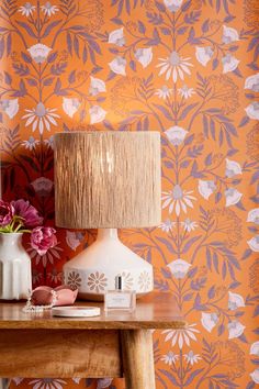 a table with two vases and a lamp on it next to a wallpaper