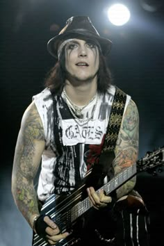 a man with long hair and tattoos playing an electric guitar