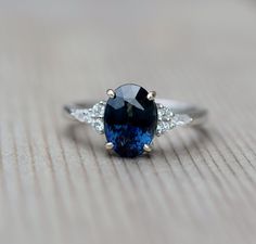 a blue and white diamond ring sitting on top of a wooden table