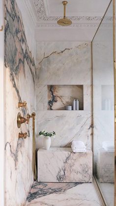 a bathroom with marble walls and flooring in white, gold and black colors is shown