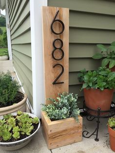 a house number sign sitting next to some potted plants