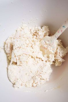 a white bowl filled with food and a plastic spoon in the top right hand corner