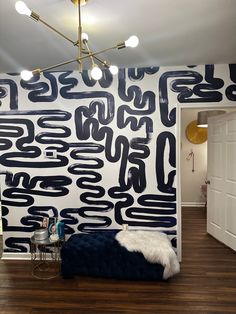 a bedroom with black and white wallpaper on the walls, wood flooring and a blue velvet bed