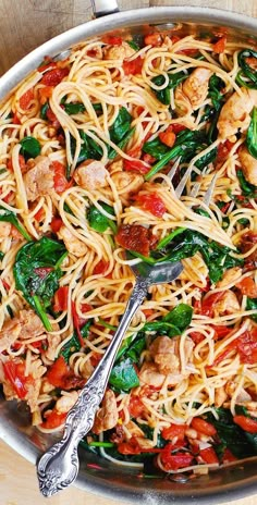 a skillet filled with pasta, spinach and chicken