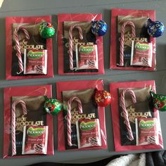 chocolate candies and candy canes are displayed on red paper bags with holiday decorations