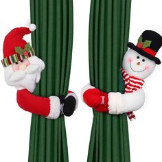 two christmas decorations hanging from the side of green curtains with santa claus and snowman