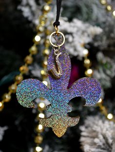 a fleur de lis ornament hanging from a christmas tree with lights in the background