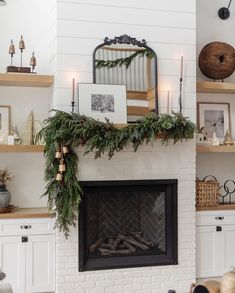 a fireplace decorated for christmas with greenery on the mantel and shelves above it