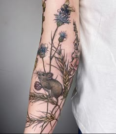 a person with a tattoo on their arm has a mouse in the middle of flowers