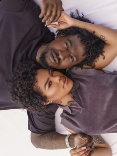 a man and woman laying on top of each other with their arms around each other