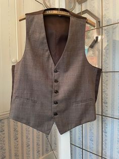 This handsome vest is made from a polyester blend in a check pattern in beige, brown, burnt orange and teal green. It has the original buttons and two front pockets. The back and lining are made from silky brown fabric. The measurements, taken with the vest lying flat, are: shoulder to shoulder, 13 inches; armpit to armpit, 21 inches; length, 25 inches in front and 22 inches in back; bottom edge, 20 inches. In very good condition. Cheap Sleeveless Brown Vest, Formal Brown Vest With Pockets, Classic Plaid Vest, Classic Plaid Sleeveless Vest, Fitted Vintage Brown Sweater Vest, Fitted Brown Vintage Sweater Vest, Vintage Fitted Brown Sweater Vest, Classic Sleeveless Plaid Vest, Tailored Brown Vest With Pockets