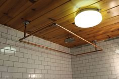 a bathroom with white tile walls and wooden ceiling, along with two lights above the toilet