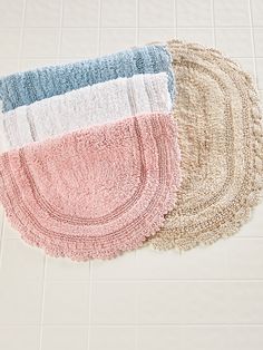 three rugs on the floor in different colors and sizes, one is pink, one is blue