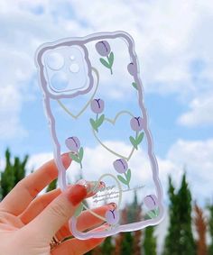 a person holding up a phone case with flowers on it and hearts drawn on the back