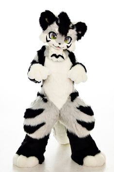 a black and white cat stuffed animal with big green eyes, standing on one leg