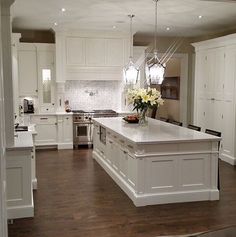 a large kitchen with white cabinets and an island