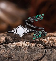 two rings with green and white stones are on top of a tree branch in the woods