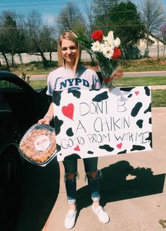 a woman holding a sign with flowers and cake