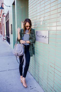 a woman leaning against a wall with her cell phone