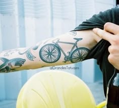 a man with a bicycle tattoo on his arm holding a beer in front of him