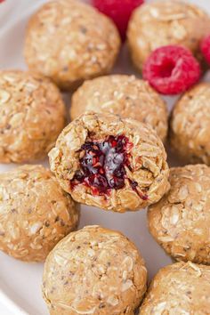 a white plate topped with oatmeal and raspberry bites covered in granola