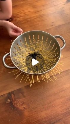 a spider in a metal bowl on top of a wooden table