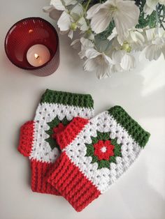 two crocheted mittens sitting on top of a table next to a candle