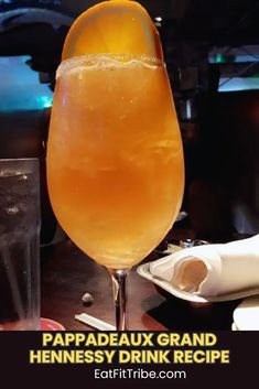 a tall glass filled with liquid sitting on top of a table next to a napkin