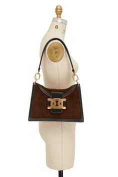 Tod's - Aoy Chain Emblem Shoulder Bag | Mitchell Stores Designer Shoulder Bag With Gold-tone Hardware For Daily Use, Luxury Tan Bucket Shoulder Bag, Designer Satchel With Gold-tone Hardware For Daily Use, Designer Handheld Bags With Gold-tone Hardware, Luxury Brown Shoulder Bag With Gold-tone Hardware, Designer Shoulder Bag With Branded Hardware For Everyday, High-end Shoulder Bag With Metal Hardware, High-end Brown Shoulder Bag With Gold-tone Hardware, Luxury Handheld Bags With Metal Hardware