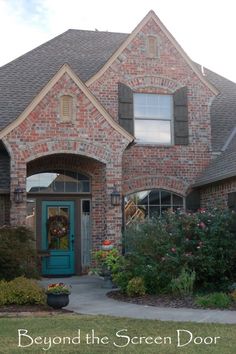 a brick house with blue front door and green shutters