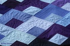 a purple and blue quilt is laying on the ground