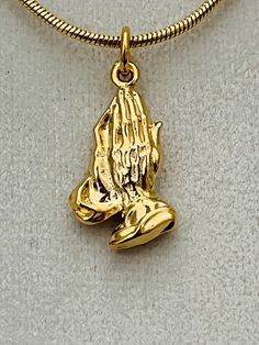 "Unique gold plated Praying Hands pendant from our family's own collection.  The pendant measures 1 1/4\" long x 1/2\" x 1mm thick and comes with a gold filled snake chain available in four sizes." Spiritual Style Large Pendant Gold-plated Jewelry, Spiritual Gold-plated Jewelry With Large Pendant, Spiritual Gold Plated Jewelry With Large Pendant, Gold Plated Jewelry With Large Spiritual Pendant, Adjustable Yellow Gold Symbolic Necklaces, Adjustable Yellow Gold Symbolic Necklace, Symbolic Yellow Gold Adjustable Necklace, Symbolic Gold Medallion Jewelry, Gold Snake Chain Charm Necklace Tarnish Resistant