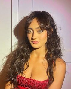 a woman in a red dress posing for the camera with her hair blowing back and eyes closed