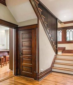 an entry way leading to a dining room and living room with wood floors, wooden stairs and white walls