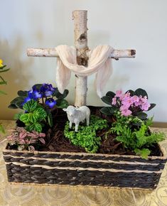 Resurrection Day planter. Purchased white birch branches at Walmart. I tied together the branches with twine and a little hot glue. Made a platform out of wood so the cross would stand upright. Then, lined the basket with black plastic. I placed the plants in the basket, with the cross and filled-in with bark mulch. I originally saw something like this in a shop which was my inspiration. They had used a large, rectangular trough filled-in with dirt, some plants, a lamb and a cross. Loved it. Christ Centered Easter Decorations, Resurrection Garden, Christ Centered Easter, Easter Resurrection, Easter Outdoor, Easter Flower Arrangements, Easter Decorations For Kids, Resurrection Sunday, Easter Garden