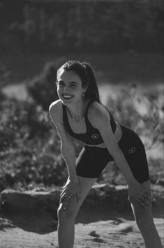 black and white photograph of a woman playing with a frisbee on the beach