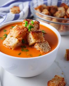 there is a bowl of soup with croutons in it