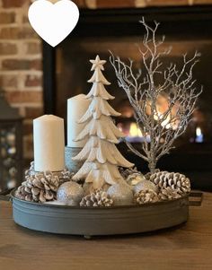 a candle holder with pine cones and candles in front of a fire place that has a heart above it