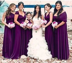 a group of women standing next to each other wearing purple dresses and holding bouquets