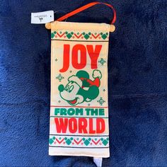 a towel hanging on the wall that says joy from the world with an image of mickey mouse