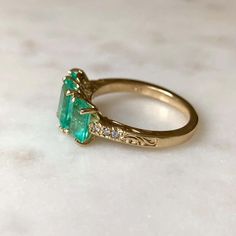 For Sale on 1stDibs - This stunning Colombian emerald 18k gold three stone engagement ring features in center; 1.40ct vs glowing-lustrous Colombian emerald measuring 7.85x6.08mm. Heirloom Emerald Ring Baguette Cut, Heirloom Style Baguette Cut Emerald Ring, Heirloom Baguette Cut Emerald Ring, Luxury Three Stone Emerald Ring For Anniversary, Luxury Three-stone Emerald Ring For Anniversary, Elegant Three Stone Emerald Diamond Ring, Elegant Three-stone Emerald Diamond Ring, Luxury Oval Emerald Ring With Three Stones, Luxury Three Stone Emerald Ring