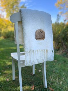 a white chair sitting in the grass with a towel on it's backrest