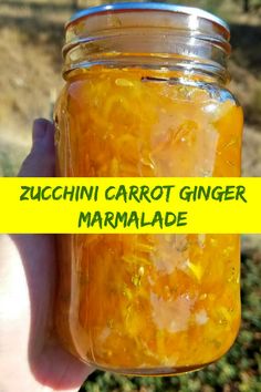 a person holding a jar filled with yellow marmalade and text overlay reads zucchini carrot ginger marmalade