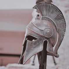 an ancient roman helmet on display in front of a stone wall with two statues behind it