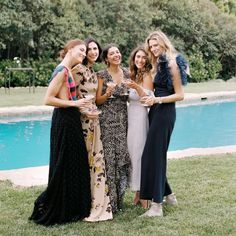 four women standing next to each other in front of a pool