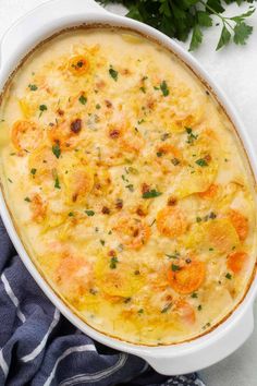 a casserole dish with cheese and vegetables in it next to a blue towel