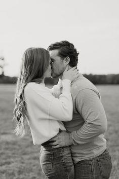 a man and woman kissing in the middle of a field