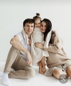 a man and two women sitting next to each other in front of a white wall